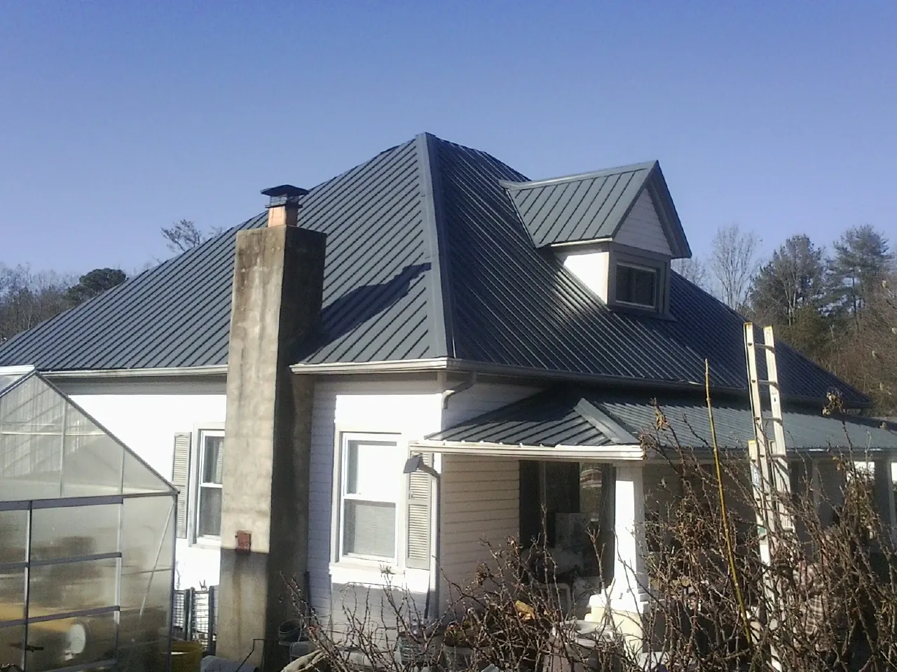 Dark blue standing seam metal roof on a white farmhouse with dormer — Slate & Tile Roof Repair by Roofing Brothers in Dayville