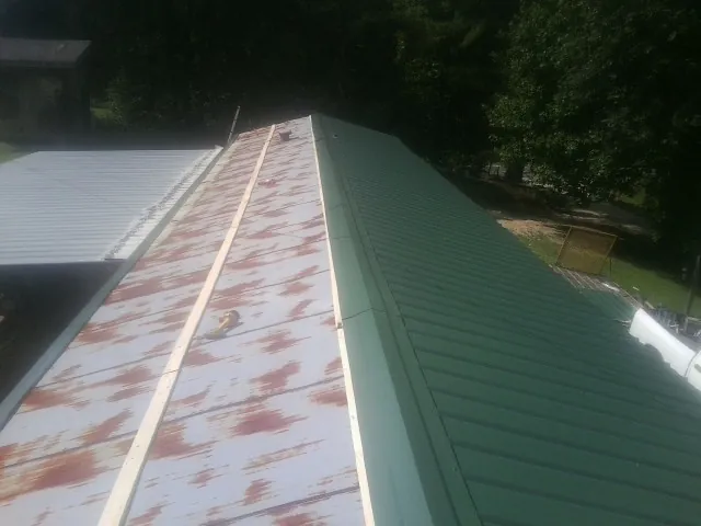 Old rusted panels beside newly installed green metal roofing — Wind Damage Roof Repair by Roofing Brothers in Dayville