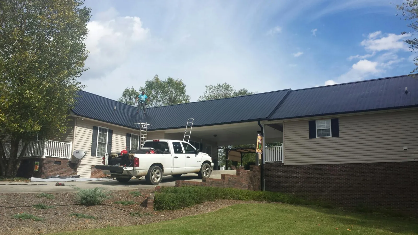 Black metal roof over a home and attached breezeway with ladders set in Dayville
