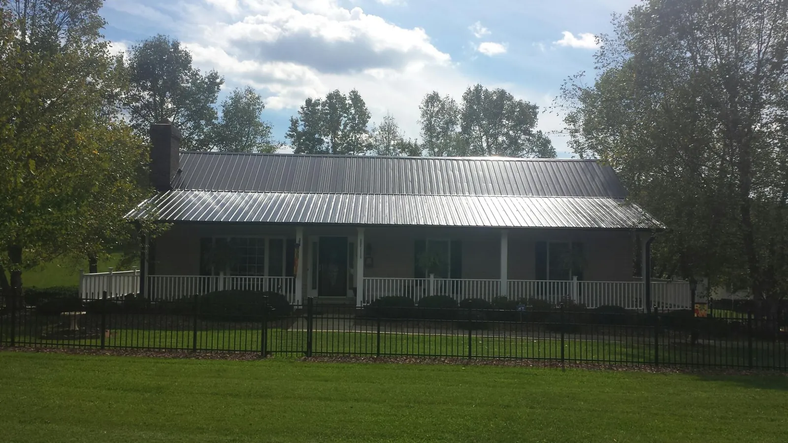 Gray metal roof on a brick ranch with a full width front porch — Gutter Guard Installation work by our crew in Dayville