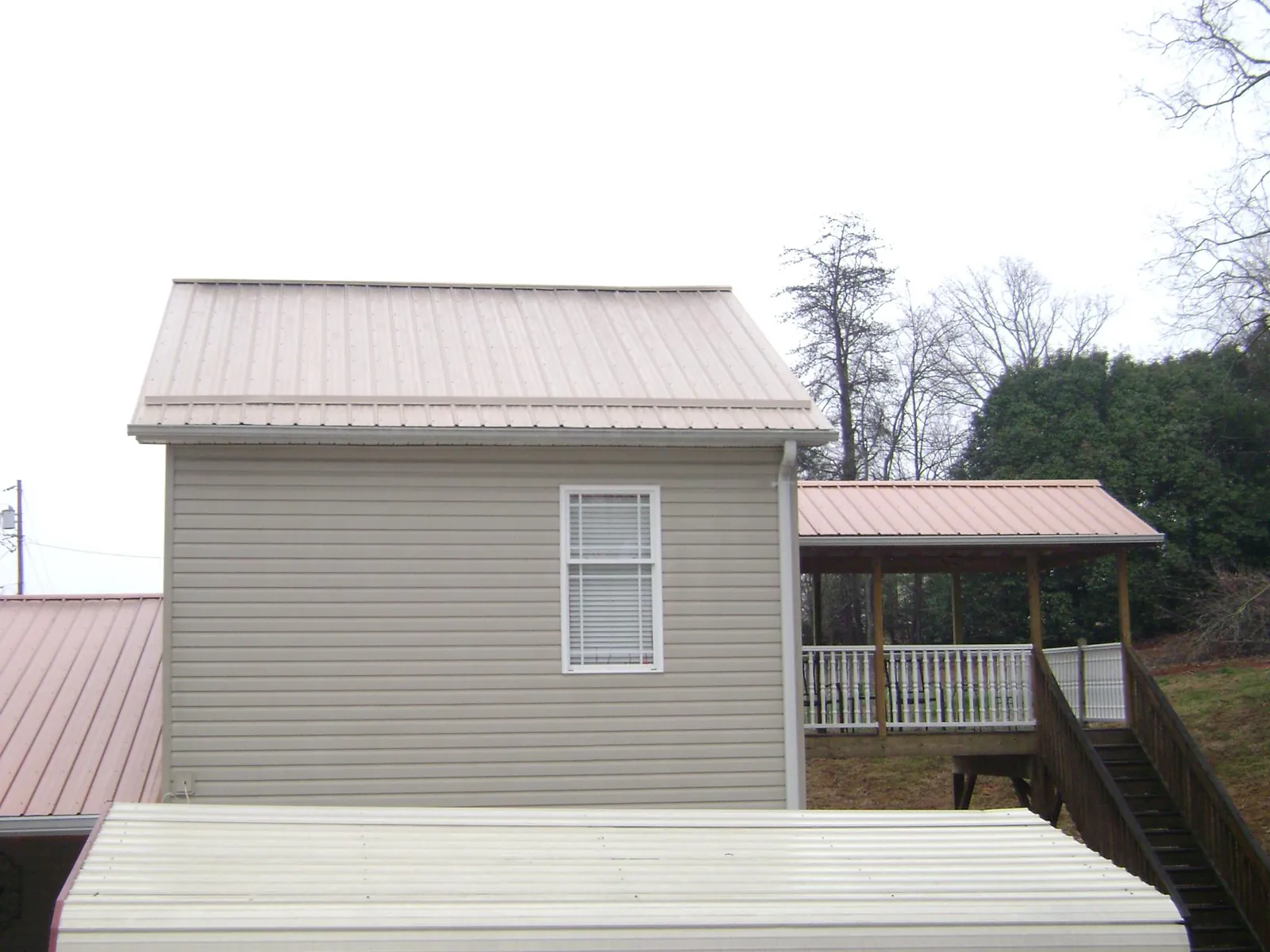 Tan metal roofs on a two story addition and attached porch, from a Roof Replacement job in Dayville