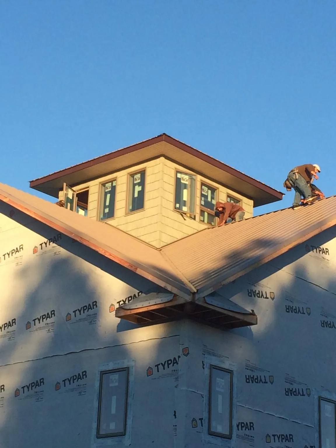 Roofers working around a rooftop cupola on a new metal roof at sunset — Roof Waterproofing in Dayville by Roofing Brothers